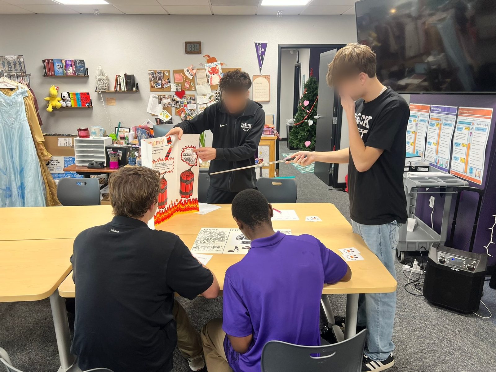 Students presenting a project on the invention of dynamite while classmates take notes