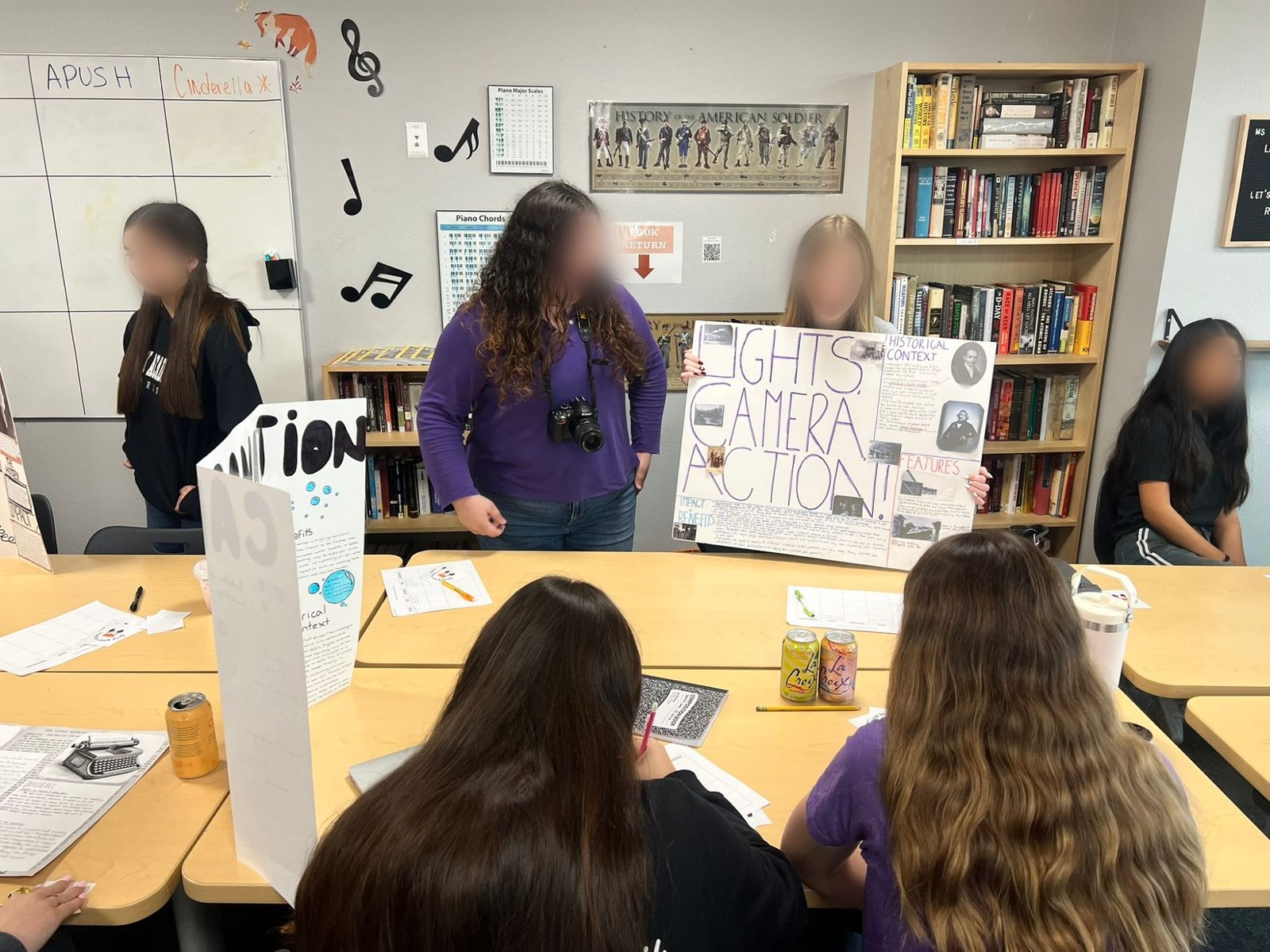 Students presenting a history-of-invention project titled Lights, Camera, Action to classmates taking notes